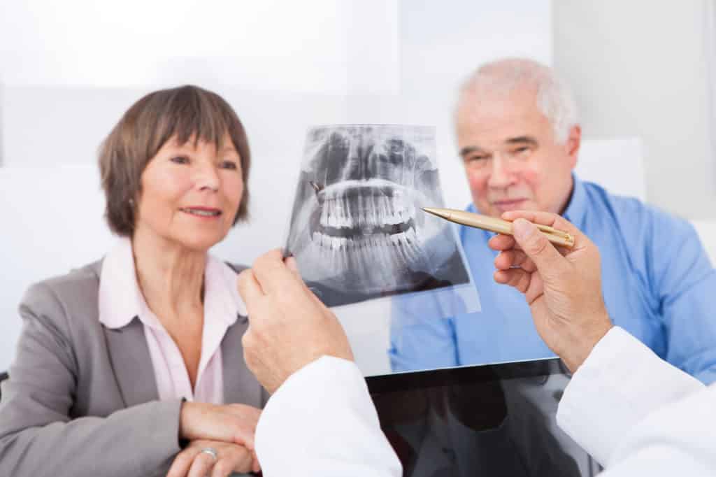 dentist showing elderly couple x-ray of teeth