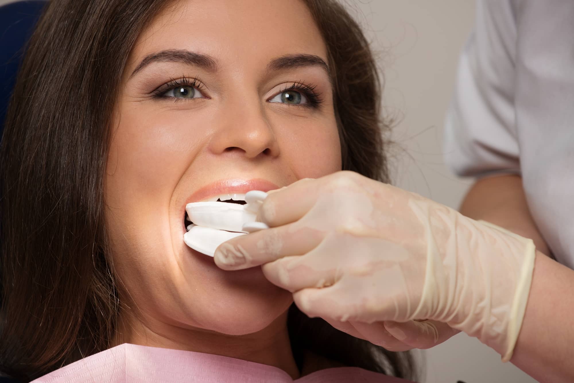 Dentist making teeth whitening procedure to female patient